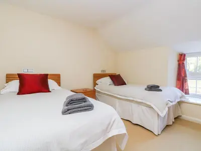 a bedroom with two beds and a window at Carne Mill in Helston