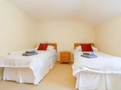 two twin beds in a room with white walls at Carne Mill in Helston