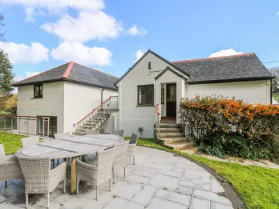 a house with a patio and a table and chairs at Carne Mill in Helston