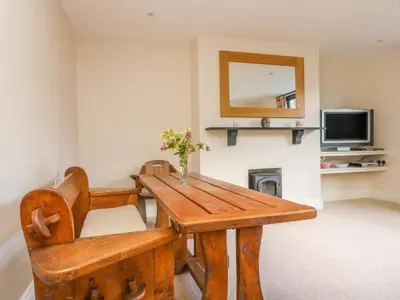 a wooden table and chair in a room with a television at Carne Mill in Helston