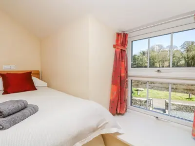 a bedroom with a bed and a large window at Carne Mill in Helston