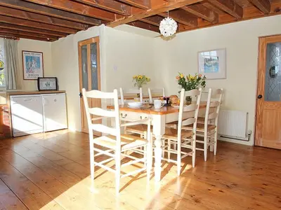 a dining room with a white table and chairs at Rose Cottage in Helston