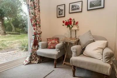 a living room with two chairs and a table and a window at Banneth in Mawgan