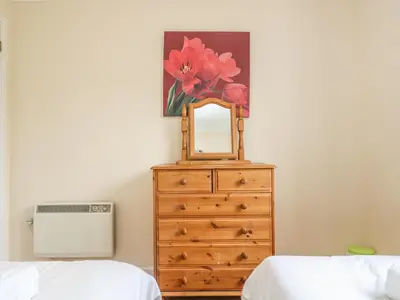 a bedroom with a dresser with a mirror on it at Cuckoo's Cottage in Falmouth
