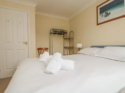 a bedroom with a large white bed with towels on it at Cuckoo's Cottage in Falmouth
