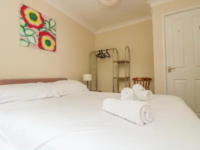 a bedroom with a white bed with towels on it at Cuckoo's Cottage in Falmouth