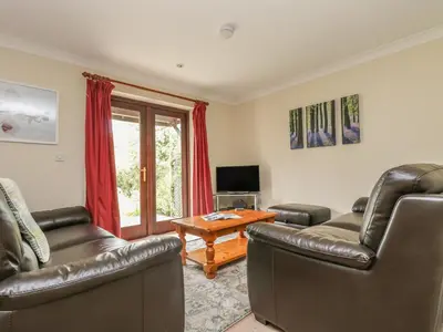 a living room with two leather couches and a television at Cuckoo's Cottage in Falmouth