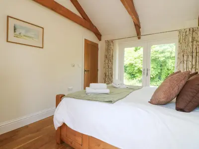 a bedroom with a large bed with a window at Roosters in Lostwithiel