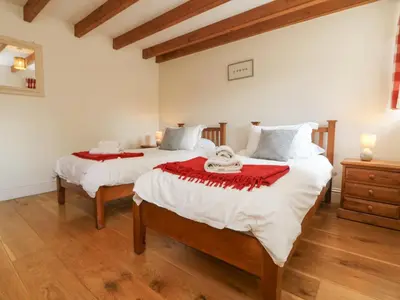 two twin beds in a room with wooden floors at Roosters in Lostwithiel