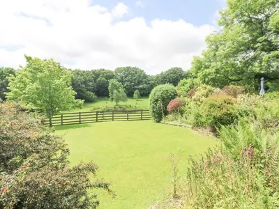 a large grassy yard with a wooden fence at Roosters in Lostwithiel