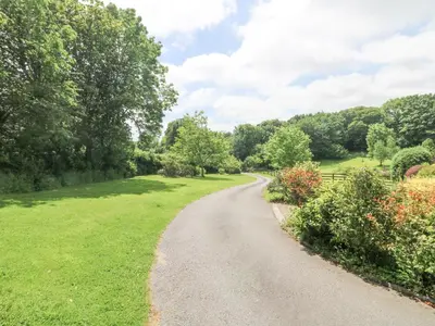 a path through a park with trees and grass at Byre in Lostwithiel