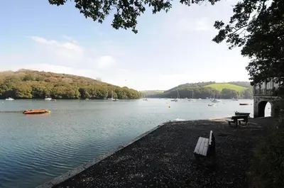 a bench sitting next to a body of water with boats at Byre in Lostwithiel