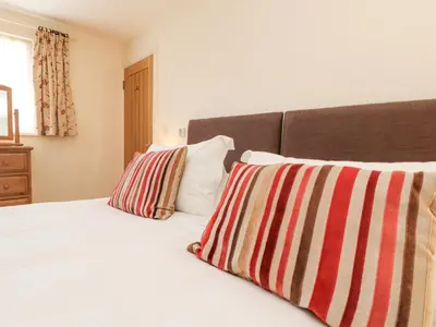 a bedroom with a white bed with two striped pillows at Byre in Lostwithiel