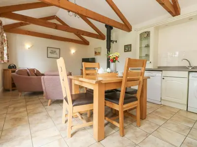 a kitchen and dining room with a wooden table and chairs at Byre in Lostwithiel