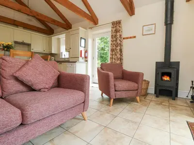 a living room with a couch and two chairs and a stove at Wagon House in Lostwithiel