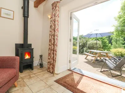 a living room with a wood stove and a patio at Wagon House in Lostwithiel