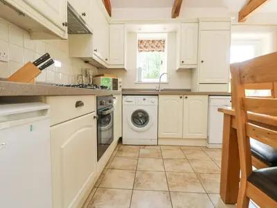a kitchen with white cabinets and a washer and dryer at Wagon House in Lostwithiel