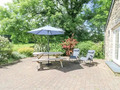 a picnic table with an umbrella and two chairs at Wagon House in Lostwithiel