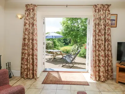 an open door to a patio with a table and chairs at Wagon House in Lostwithiel