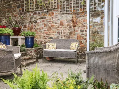 a patio with wicker chairs and a brick wall at Seabien in Falmouth