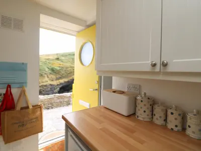 a kitchen with white cabinets and a wooden counter top at Kerbenetty Harbour Cottage in Portloe