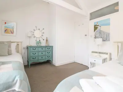 a bedroom with two beds and a blue dresser at Kerbenetty Harbour Cottage in Portloe