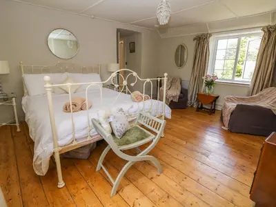 a bedroom with a white bed and a chair at Parwin in Tintagel