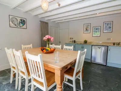 a kitchen and dining room with a wooden table and chairs at Parwin in Tintagel