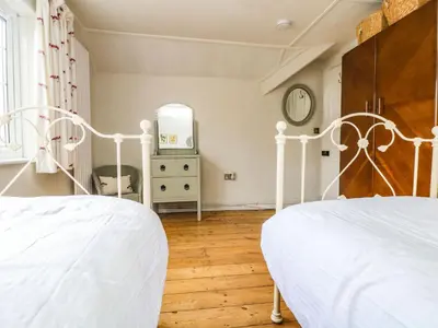 a bedroom with two white beds and a mirror at Parwin in Tintagel