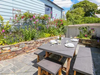 a table and chairs on a patio with flowers at Parwin in Tintagel