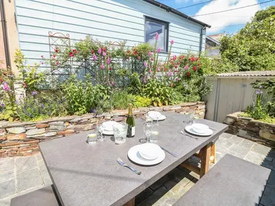 a table with plates and wine glasses on a patio at Parwin in Tintagel