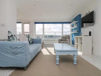 a living room with a blue couch and a table at St Ives View in Porthtowan