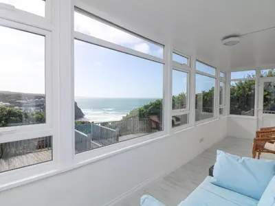 a living room with large windows and the ocean at St Ives View in Porthtowan