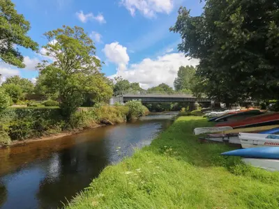 a river with a bridge and boats on it at Riverview in Lostwithiel