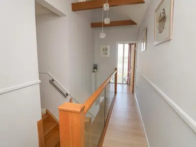 a staircase in a home with white walls and wood floors at Tides in Padstow
