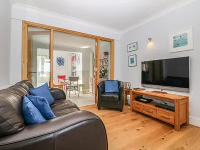 a living room with a leather couch and a flat screen tv at Tides in Padstow