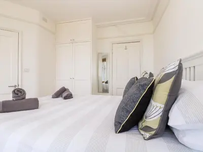 a white bedroom with a large bed with pillows at Porthmeor Beach House in St Ives