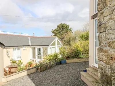 a cottage with a garden in front of a house at Mynheer Farm Bowji in Redruth