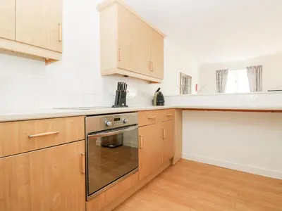 a kitchen with wooden cabinets and a dishwasher at Rosemary Cottage in Falmouth