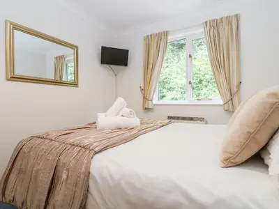 a bedroom with a large white bed and a window at Rosemary Cottage in Falmouth