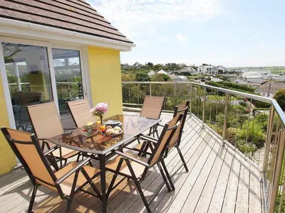 a wooden deck with a table and chairs on a balcony at Windrush in Newquay