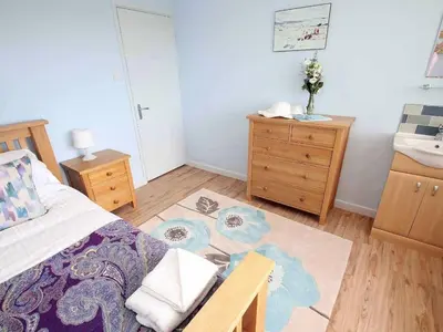a bedroom with a bed and a dresser and a sink at Windrush in Newquay