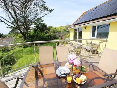 a glass table with flowers on top of a balcony at Windrush in Newquay
