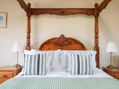a bedroom with a bed with a wooden headboard and pillows at Marhayes in Camelford