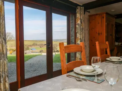 a dining room with a table and a view of the countryside at Westhayes in Camelford
