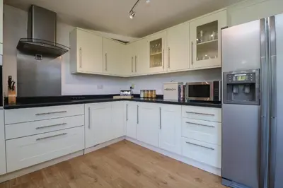 a white kitchen with white cabinets and appliances at Penhaven in Bude