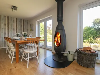 a fireplace in a living room with a dining room table and a dining room at Penhaven in Bude