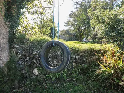 a tire is hanging on a stone wall at Penhaven in Bude