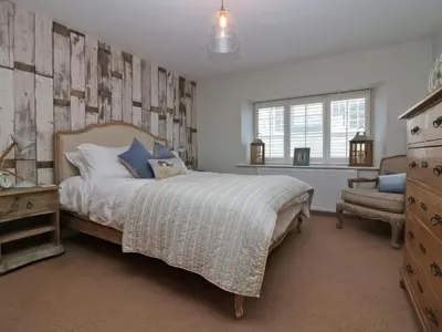 a bedroom with a bed and a chair in it at Trelan in St Austell