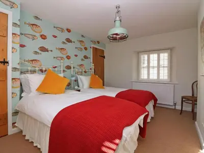 a bedroom with two beds with red and orange pillows at Trelan in St Austell